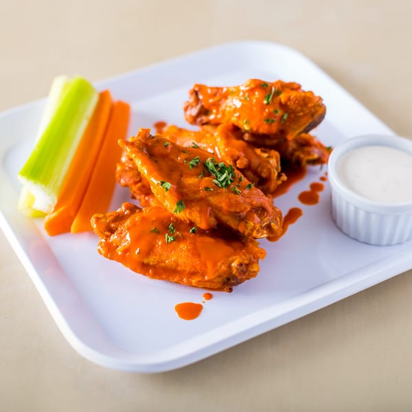 House of Wings' buffalo wings, garnished with parsley, served with celery, carrots, and ranch dressing.