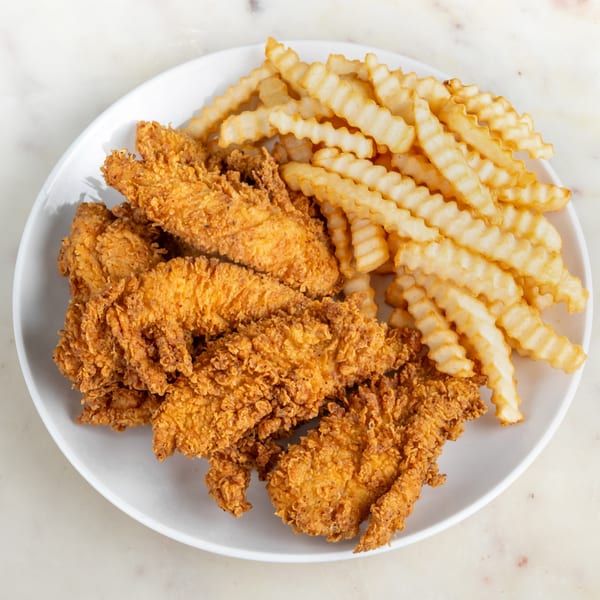 Crispy fried chicken tenders and crinkle-cut fries on a white plate from House of Wings.