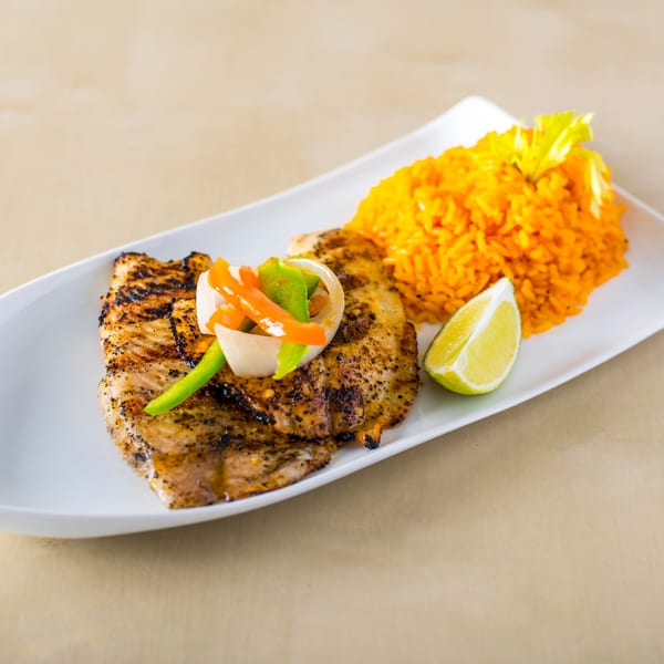 Grilled chicken with colorful peppers and onions, orange rice, and a lime wedge on a white plate.