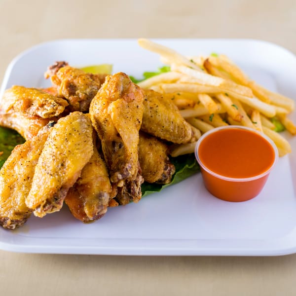 House of Wings' golden fried wings with french fries, a lime wedge, and hot sauce.