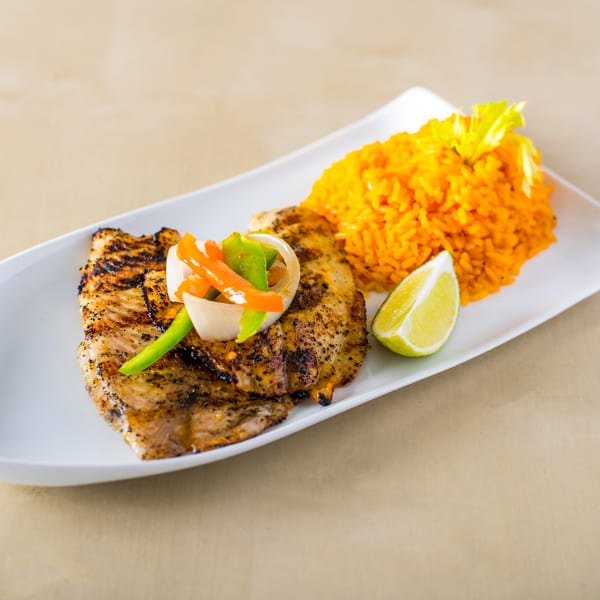 Grilled chicken with peppers, onions, orange rice, and a lime wedge on a white plate.